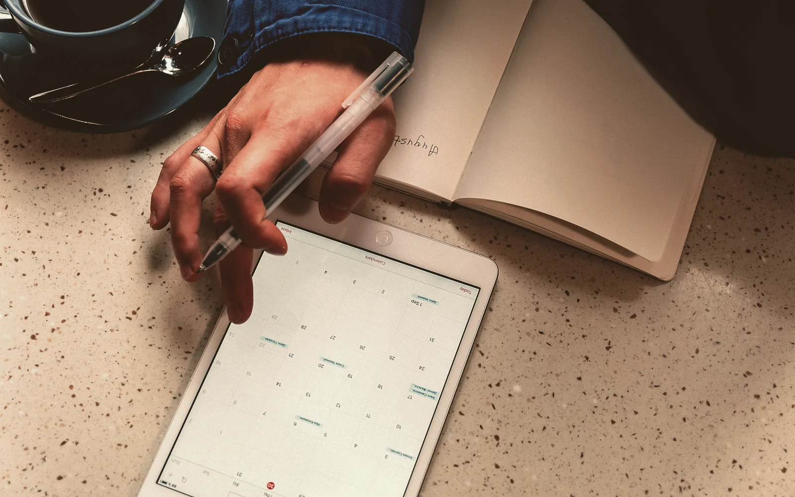 An operations manager and a crew member lean over a desk, pointing at a line on a printed job schedule next to an open laptop