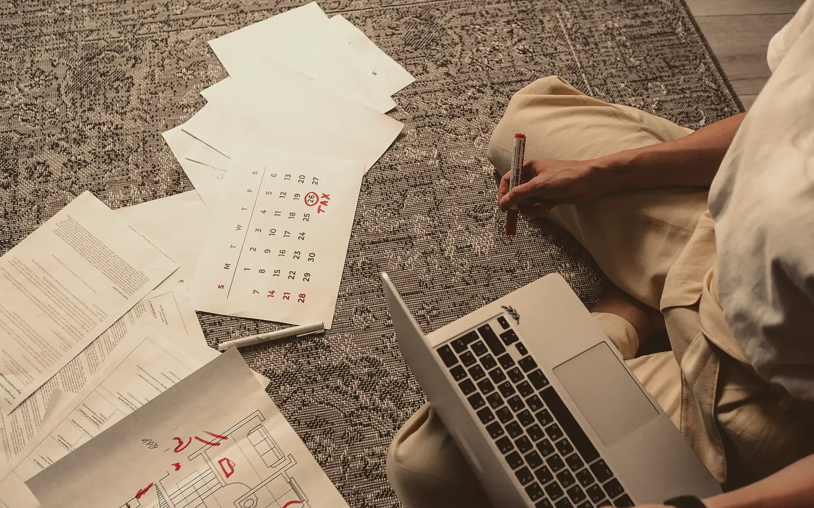Dos compañeros de trabajo frente a un calendario de pared en una oficina pequeña, uno marca fechas con un marcador y el otro sostiene un cronograma impreso y señala una semana.