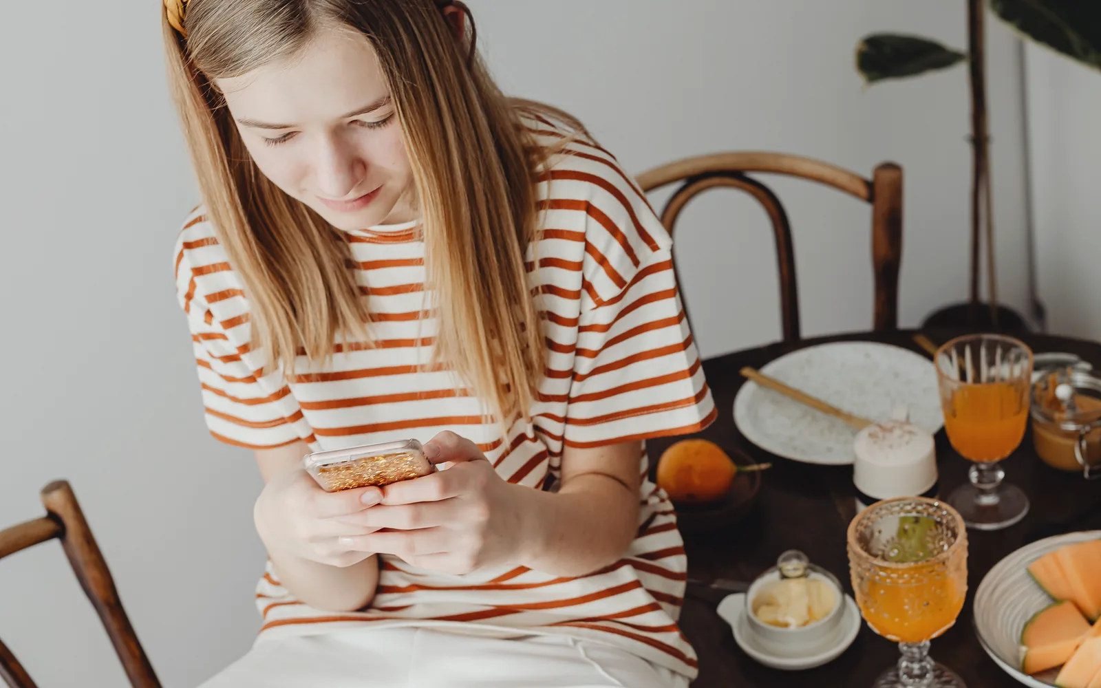 A woman checks her phone at her own breakfast table, before any ad reaches her